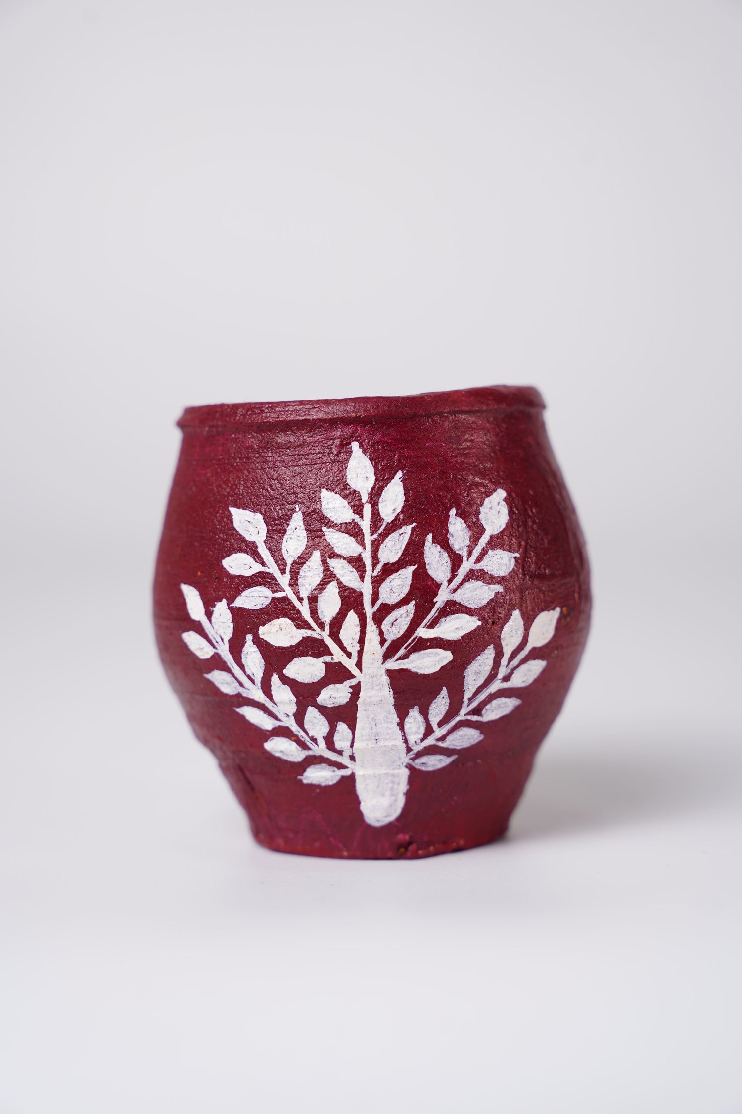 small, handcrafted terracotta pot decorated with traditional Warli art